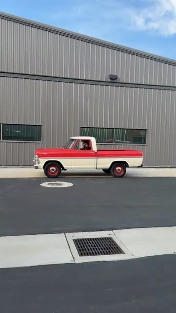 Red and white vintage Ford truck outside the workshop